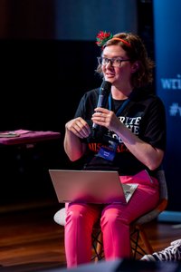 Felicity Brand sitting in a chair, holding a microphone