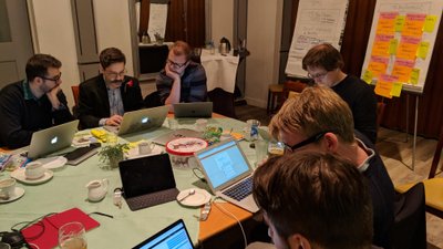 Group of people collaborating at a table with multiple computers