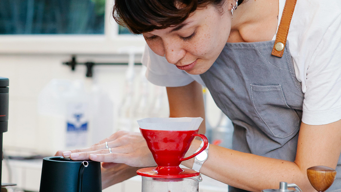 A young woman making pour-over coffee as a metaphor for a marketer tending her clients' case studies