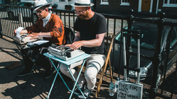 Two men typing on a city street