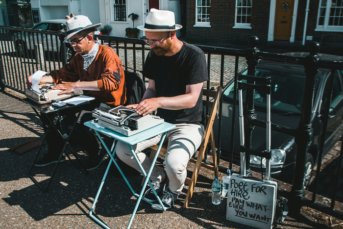 Two men at typewriters on a city street