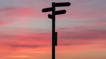 Directions signpost against a sunset sky