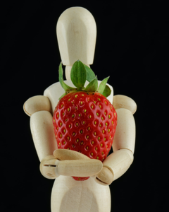 Wooden human drawing figure hugging a strawberry